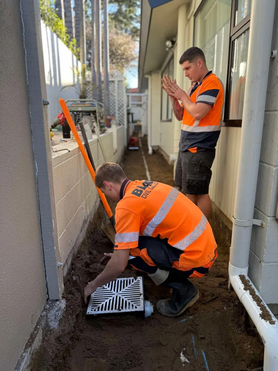 Residential drainage being installed alongside a new build before the slab goes down, with separate stormwater and wastewater trenches open across the site
