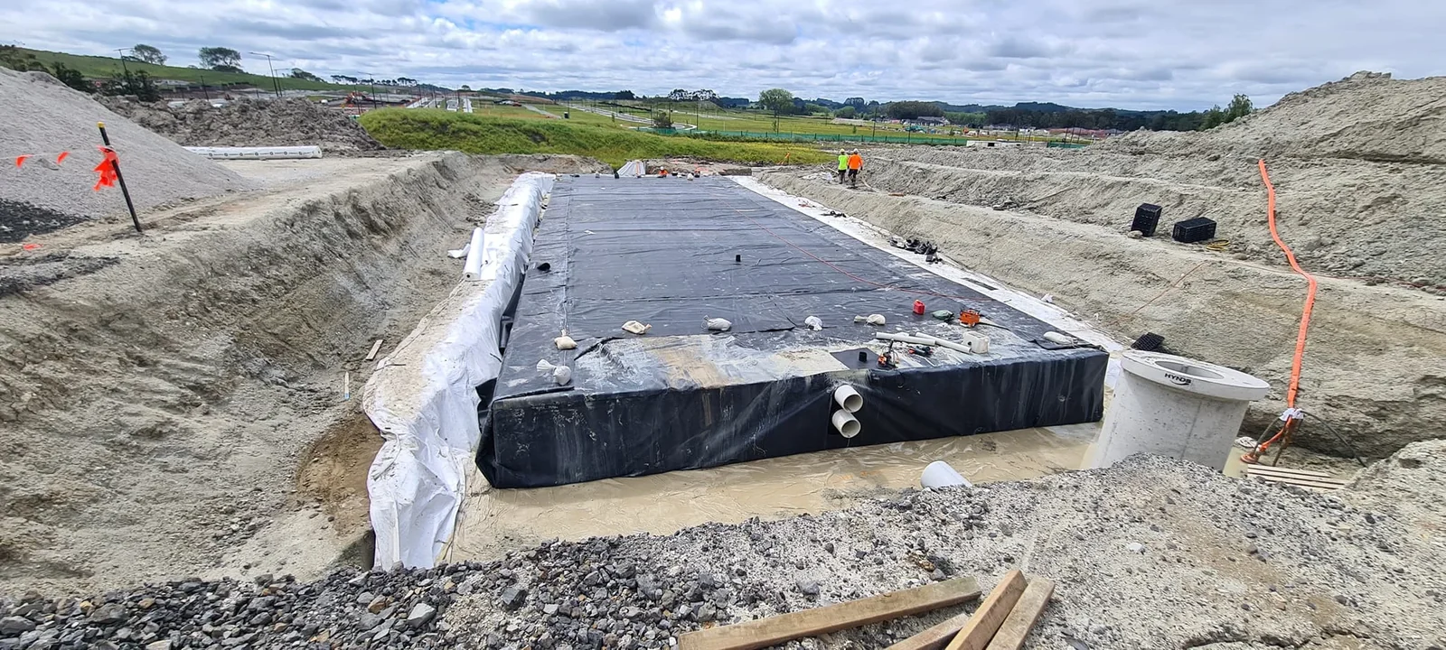 A stormwater detention tank being lowered into an excavated trench on an Auckland clay site during a residential drainage install