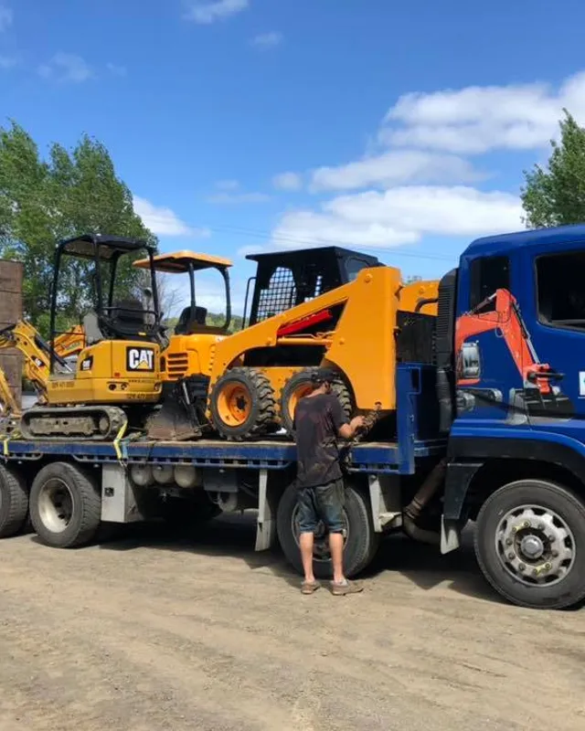 Blake Civil Construction truck loaded with CAT excavator and skid steer heading to an Auckland job site